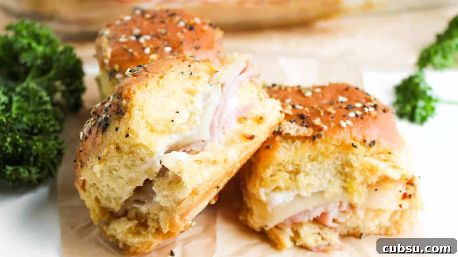 7 Holiday Ham Recipes to Make Dinner Feel Just Right 6 Three ham and cheese sliders on seeded buns are placed on parchment paper. Bright green parsley is visible in the background.