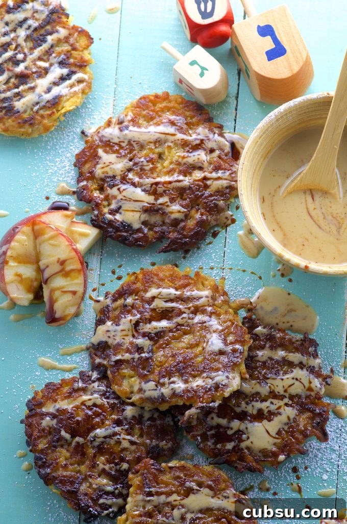 Bird's eye view of Apple potato latkes with Silan tahini sauce on a blue surface