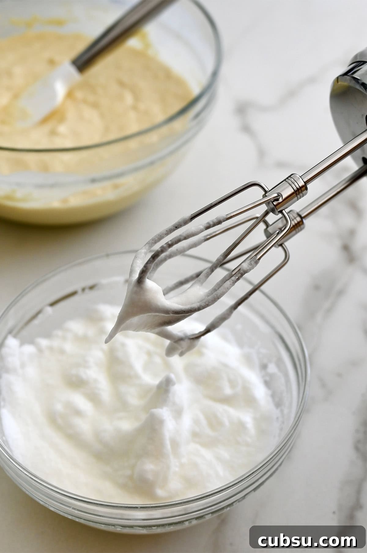 Crispy Belgian Waffles Recipe for Brunch and Weekend Mornings 7 An electric mixer hovers over a bowl containing whipped egg whites.