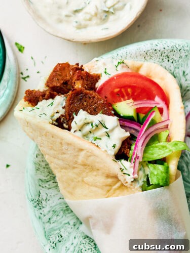 Seitan Vegan Gyros: Flavorful Plant-Based Greek Wrap Recipe 17 A Greek-inspired Vegan Gyros with tzatziki and tomato on a dinner plate.