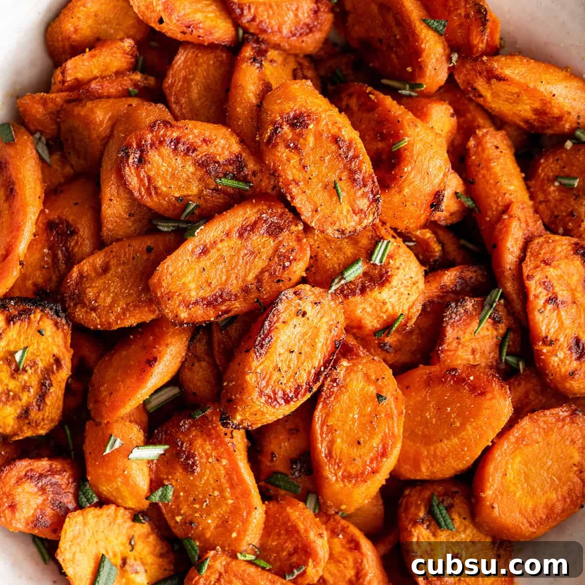 up close overhead view of Oven Roasted Carrots in a bowl garnished with herbs