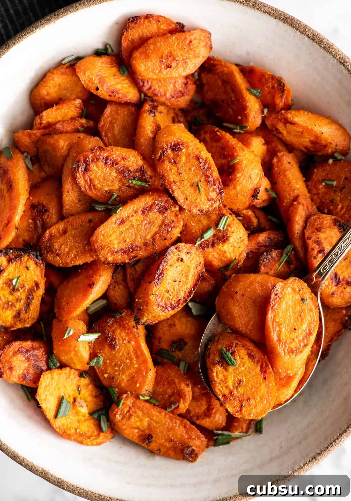 overhead photo of a spoon taking a scoop of roasted carrots out of a bowl