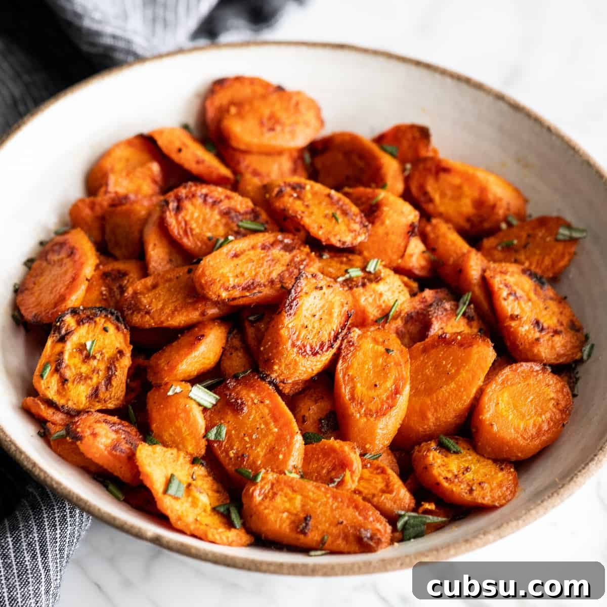 front view of roasted carrots in a bowl garnished with chopped rosemary