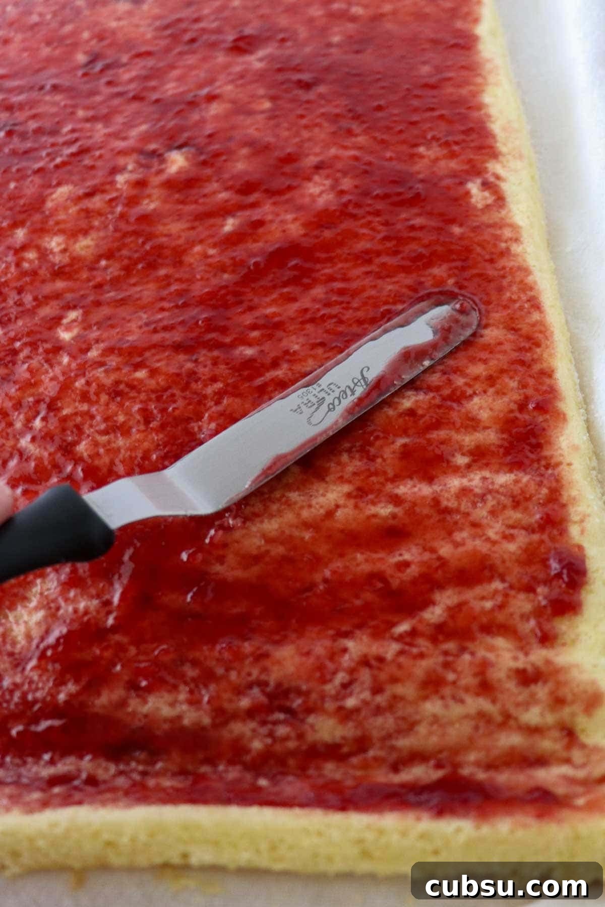 Swedish Rulltårta being spread with raspberry jam.