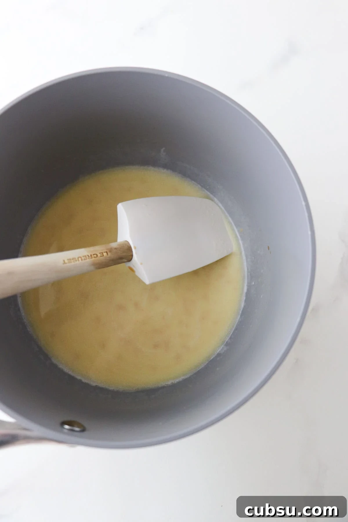 Butter and milk melted together in a saucepan with a rubber spatula.