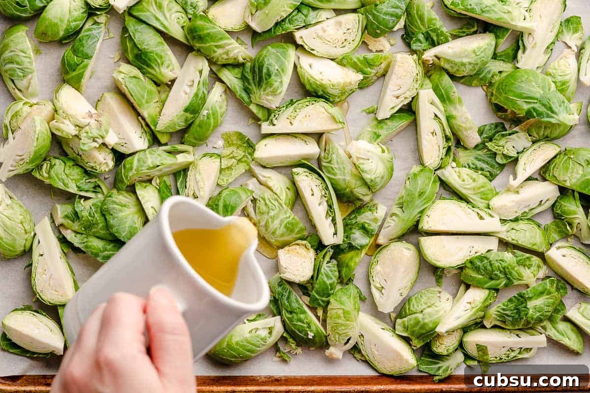 small pitcher of oil being drizzled over brussels sprouts