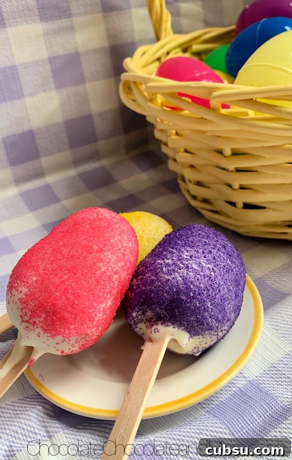 Easter Egg Cake Pops 3 Easter Egg Cake Pops (one with yellow sprinkles, one with pink, and one with purple) sitting on a white with yellow rimmed plate and a yellow basket filled with plastic colored easter eggs sitting on a purple and white plaid background.