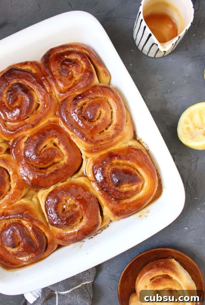 Lemon Glazed Sweet Rolls Recipe – Soft, Zesty Breakfast Buns 4 Lemon Rolls topped with lemon drizzle viewed from above in a white baking dish.