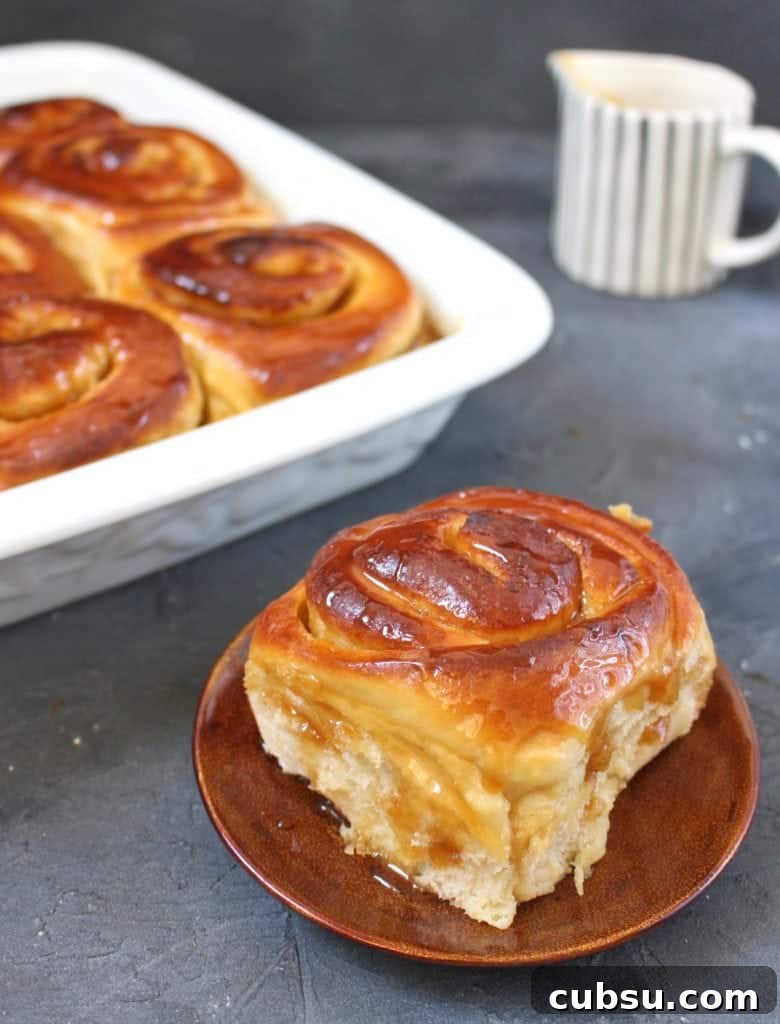 Lemon Glazed Sweet Rolls Recipe – Soft, Zesty Breakfast Buns 6 One roll on a small brown plate with the baking dish in the background.