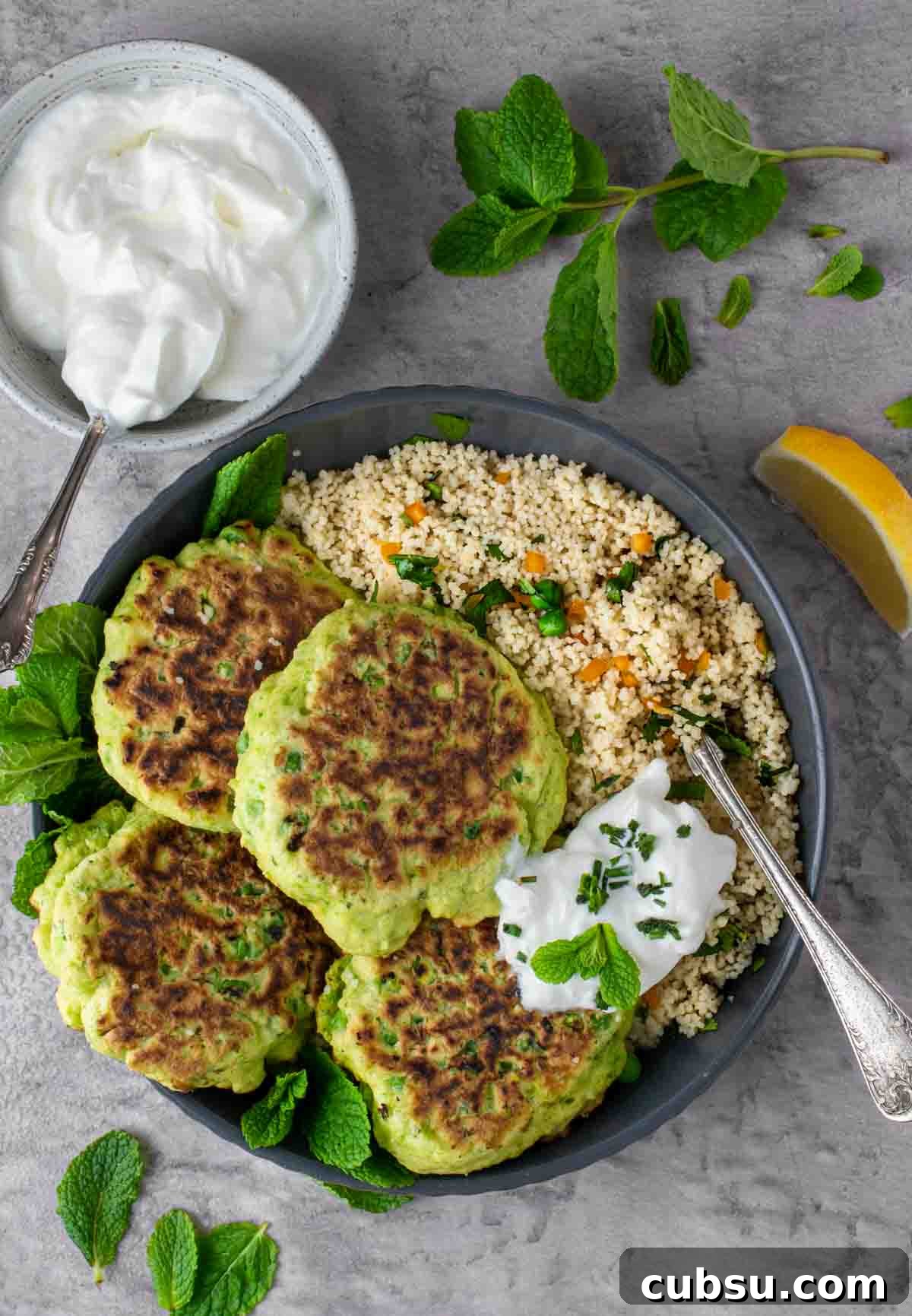Crispy Cheesy Green Pea Fritters Recipe 2 Four pea fritters in a bowl with a portion of couscous. and a dollop of greek yoghurt.