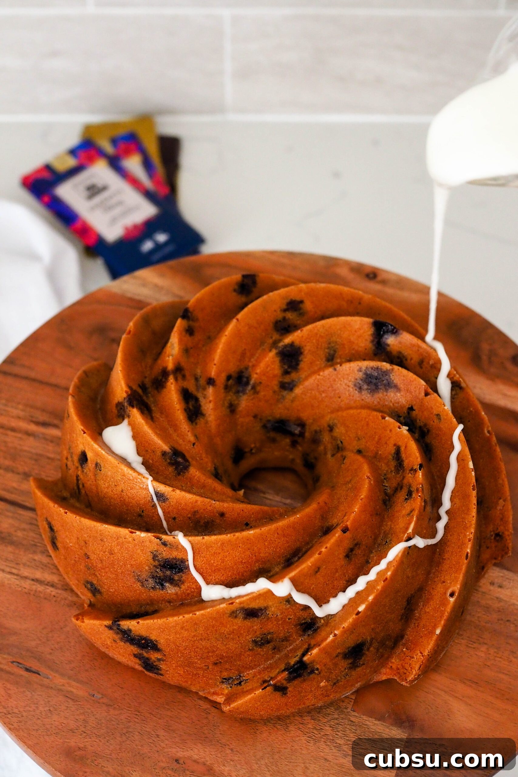 White icing is drizzled over a baked Bundt cake.