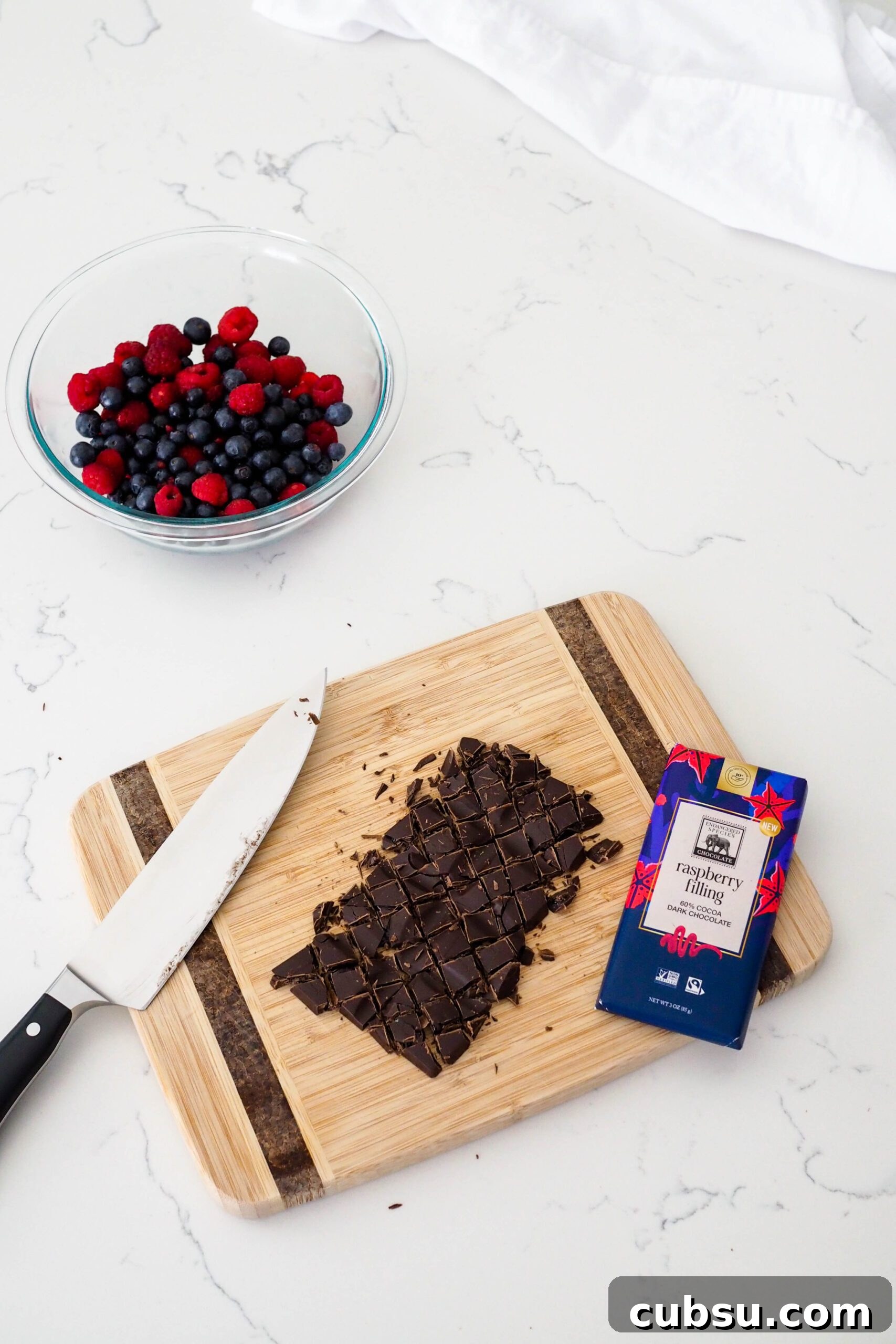A chopped chocolate bar on a wooden cutting board.