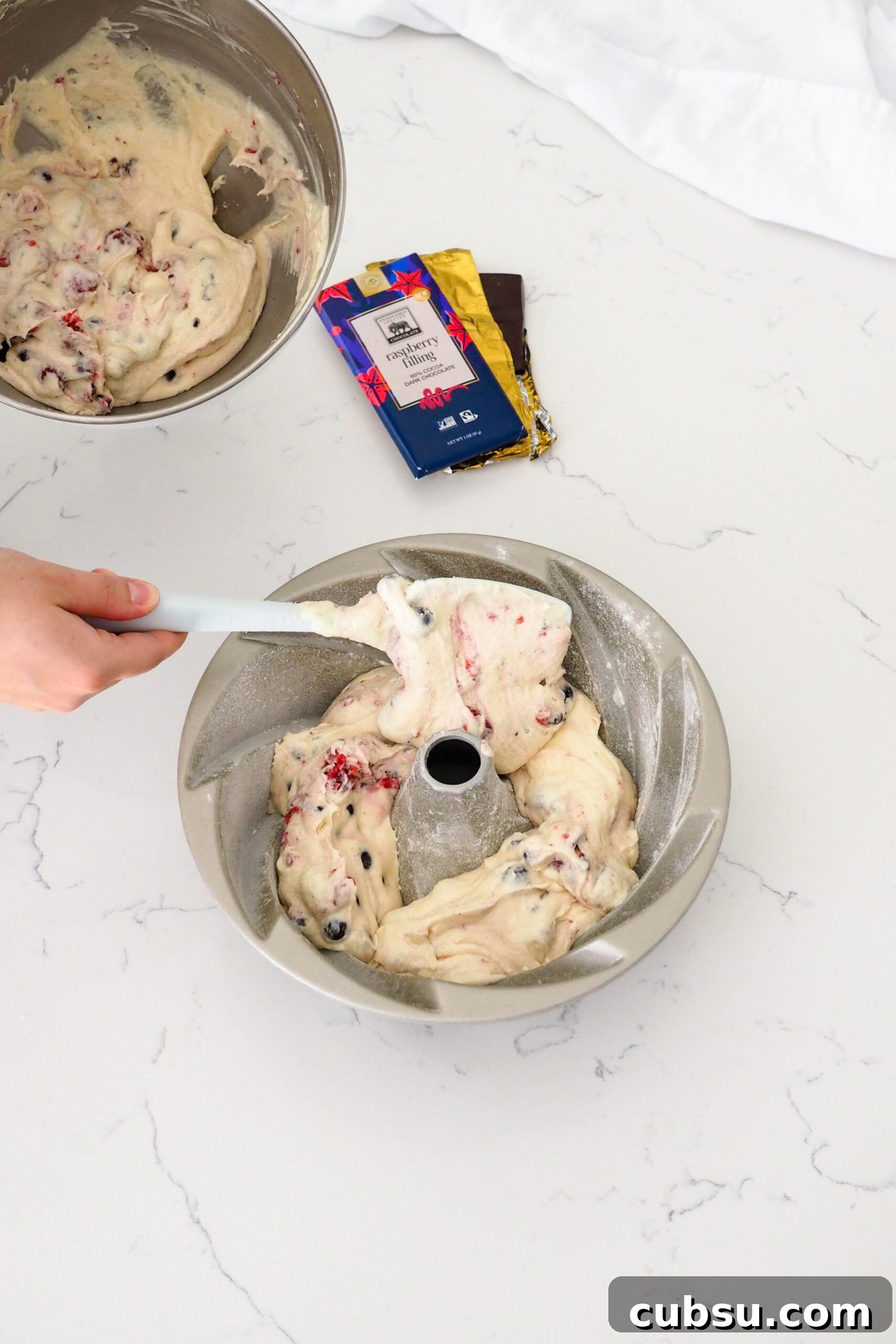 A spatula spoons batter into a prepared Bundt pan.