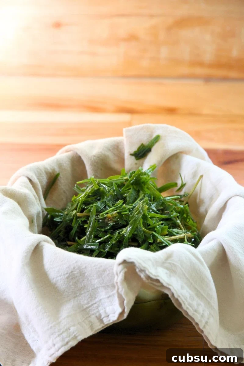 Lavender plant matter being filtered from oil in a cloth. 