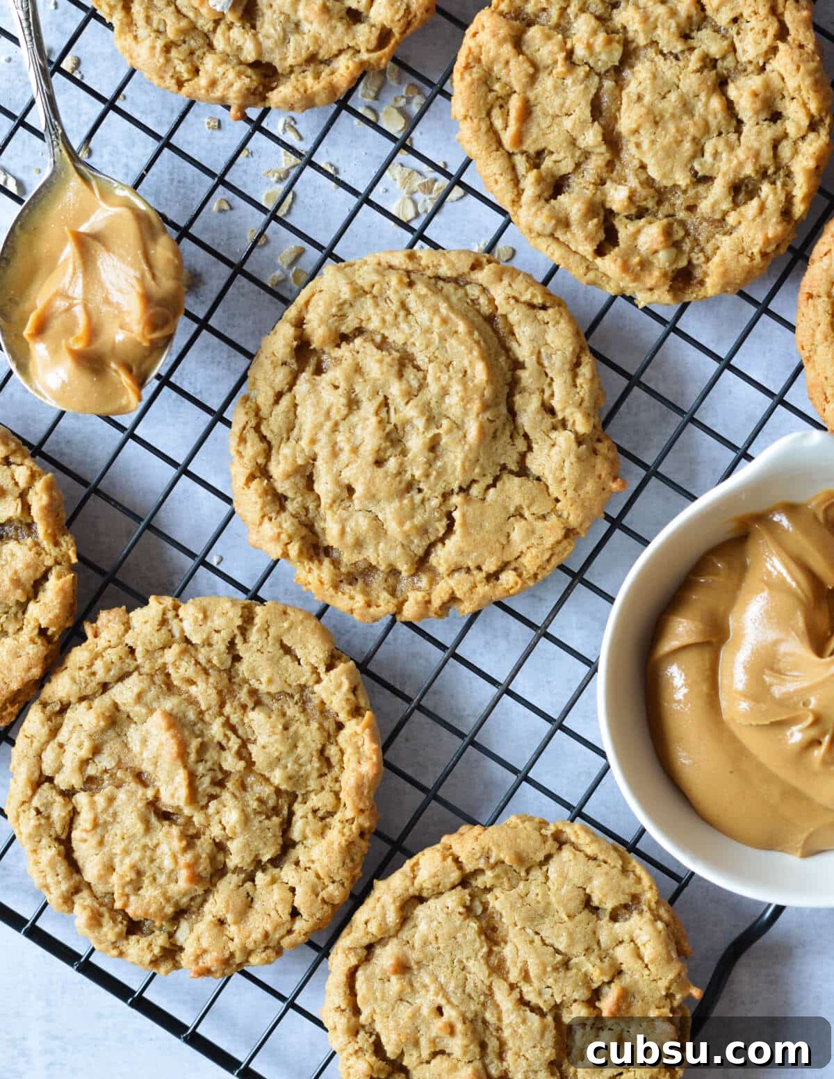 Flourless Peanut Butter Cookies Recipe — Chewy & Gluten-Free 2 peanut butter cookies on a wire rack near a bowl of peanut butter.
