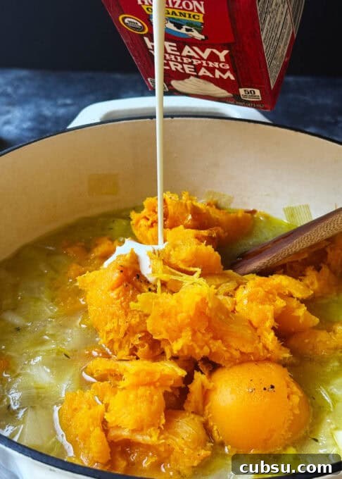 Cream is being poured over the butternut squash in the pot