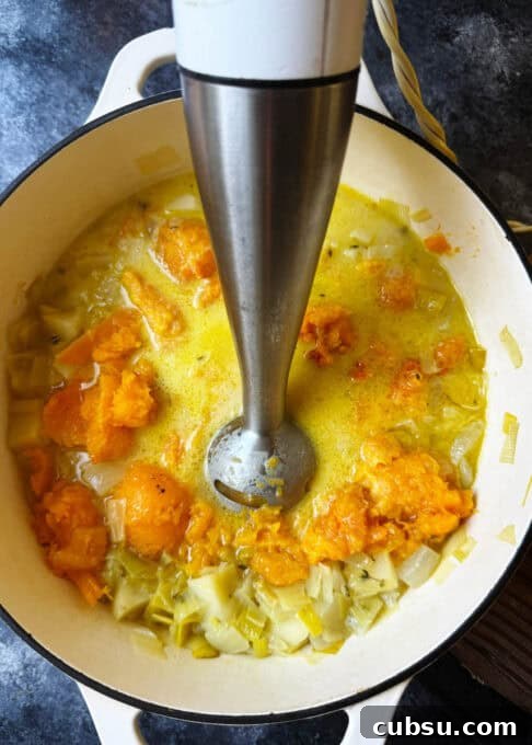 Soup is being pureed with an immersion blender