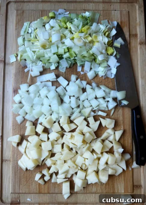 Chopped up onions, leeks and potatoes on a chopping board