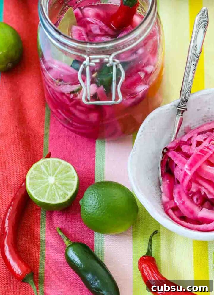 Mexican pickled red onions in a clamp jar and white bowl with chiles and limes on a colorful striped cloth.