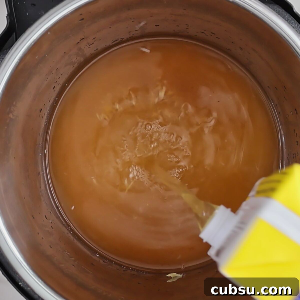pouring chicken stock into instant pot.