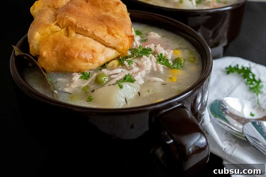 chicken pot pie soup with a roll in a bowl