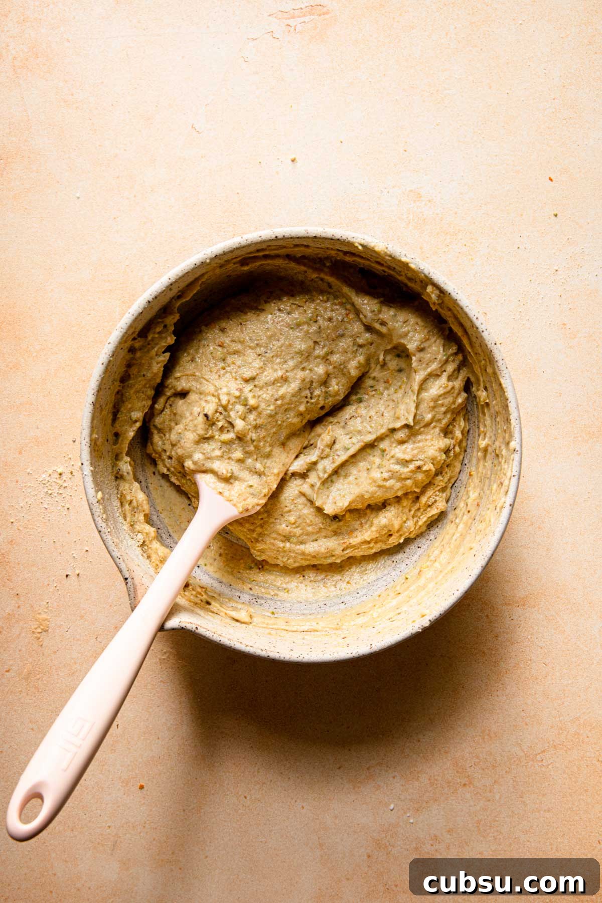 a mixing bowl with a cake batter and a spatual.