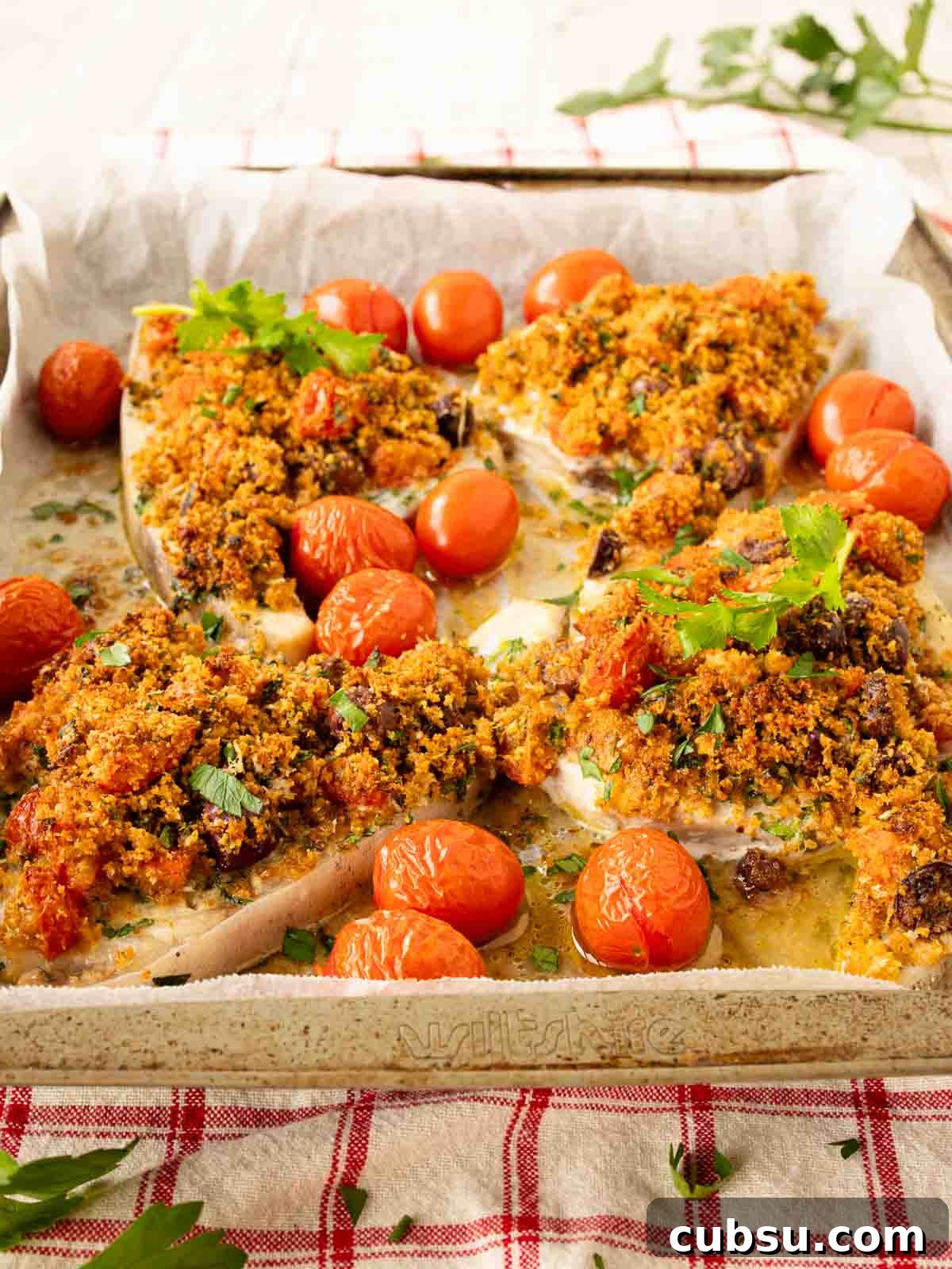 Baked Swordfish with a gratin topping surrounded by baked cherry tomatoes.
