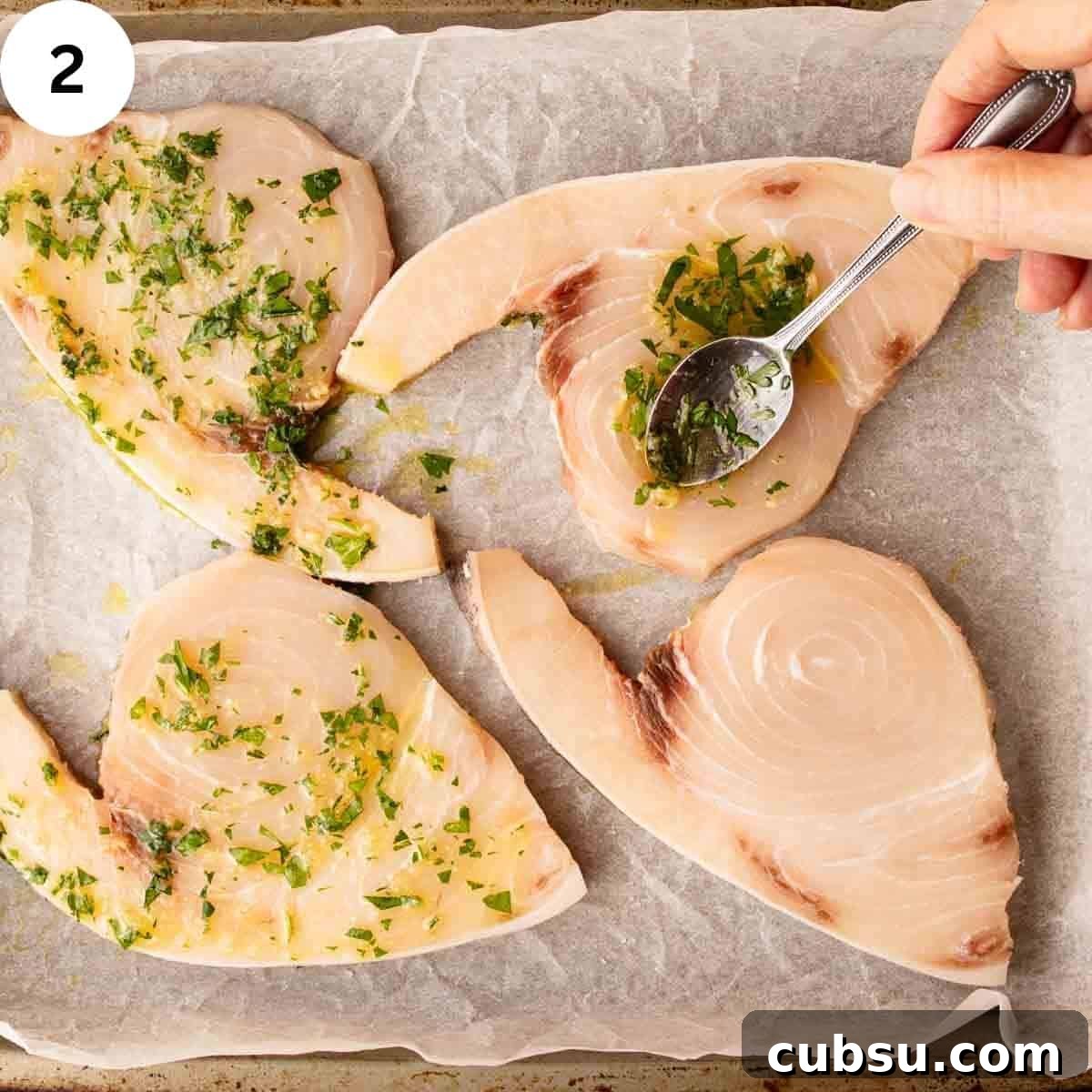 Using a spoon to drizzle herb dressing on swordfish steaks.