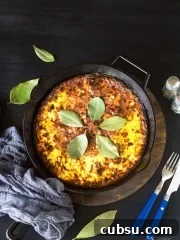Bobotie in a cast-iron skillet on a black background.