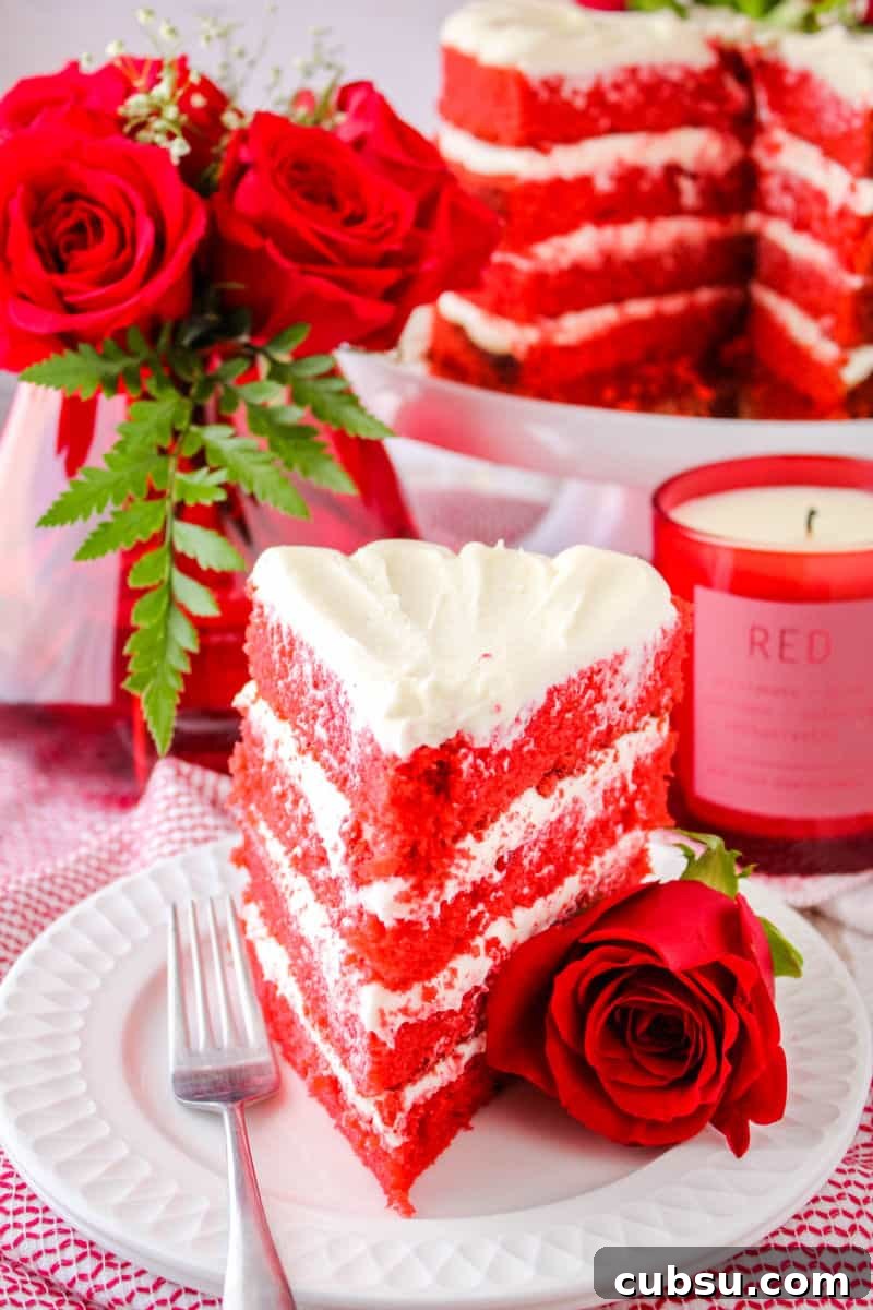 slice of velvet cake on a plate with a fork and a rose