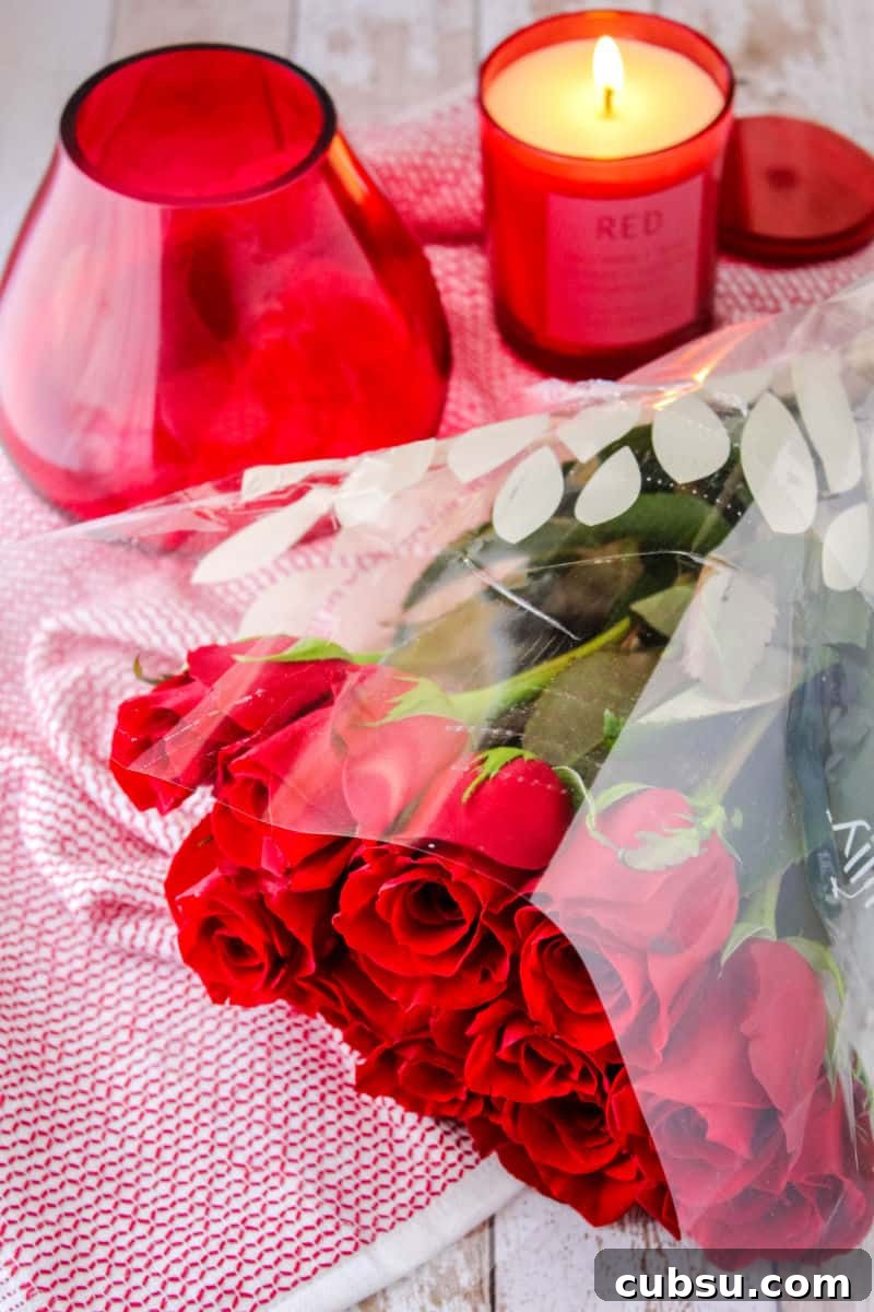 red teardrop fower vase, bouquet of red roses and a red candle