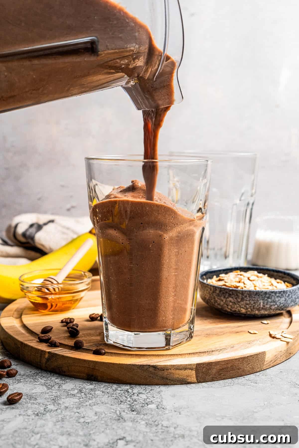 Pouring a smoothie from a blender and into a drinking glass. Pouring a smoothie from a blender and into a drinking glass.
