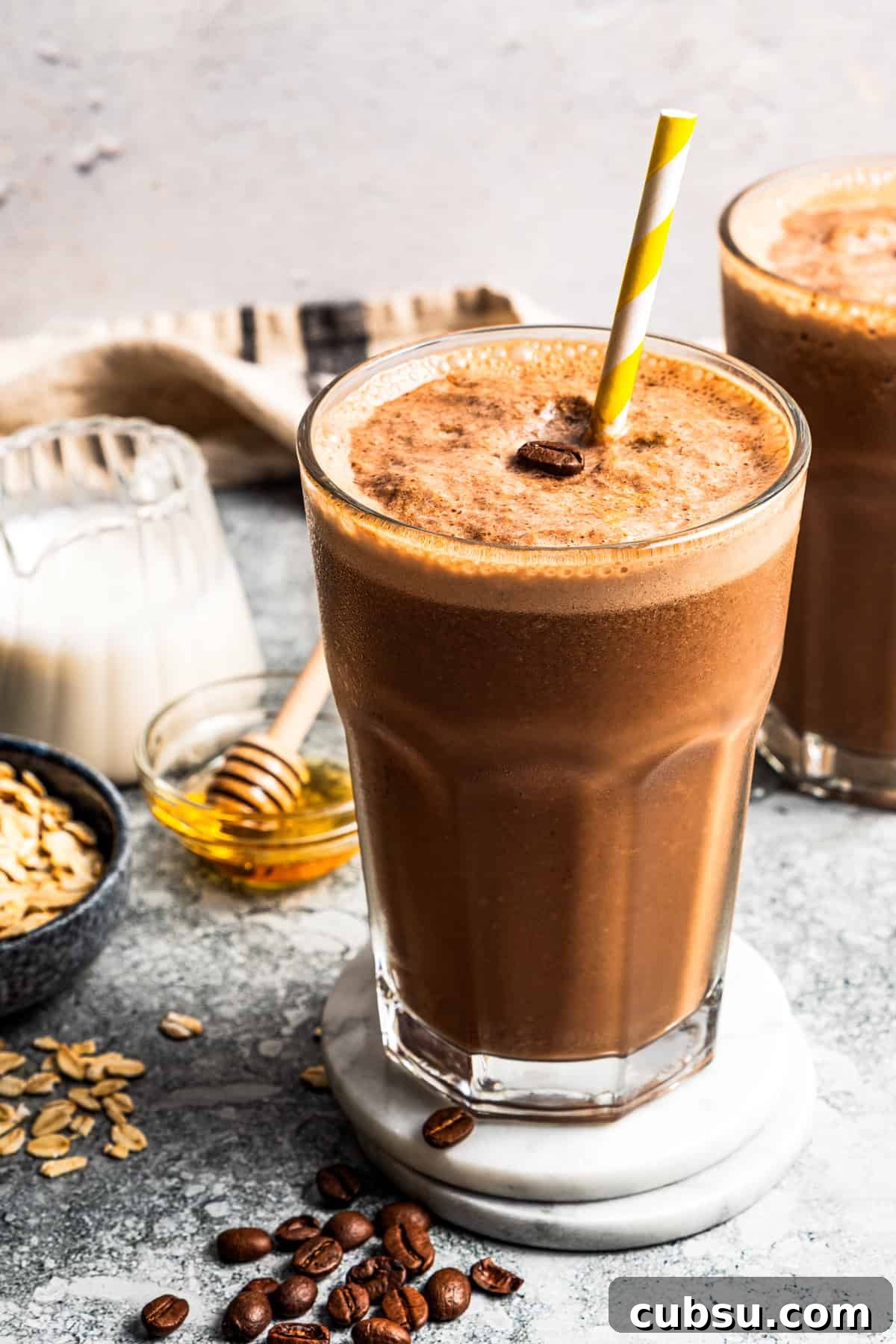This creamy coffee smoothie is a delicious and satisfying way to start busy mornings! It’s packed with oats, flaxseed, and bananas for a flavorful, filling treat. Coffee smoothie in a drinking glass with a straw.