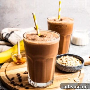Creamy Iced Coffee Smoothie Recipe for Morning Energy 2 A coffee smoothie in a tall glass with a straw and a second smoothie next to a bowl of oats in the background.