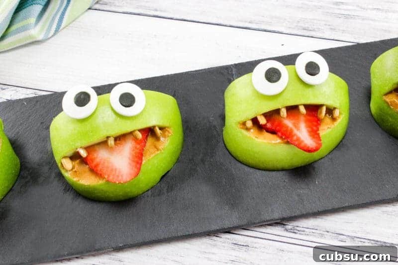 Green apple monster snacks on black serving tray.