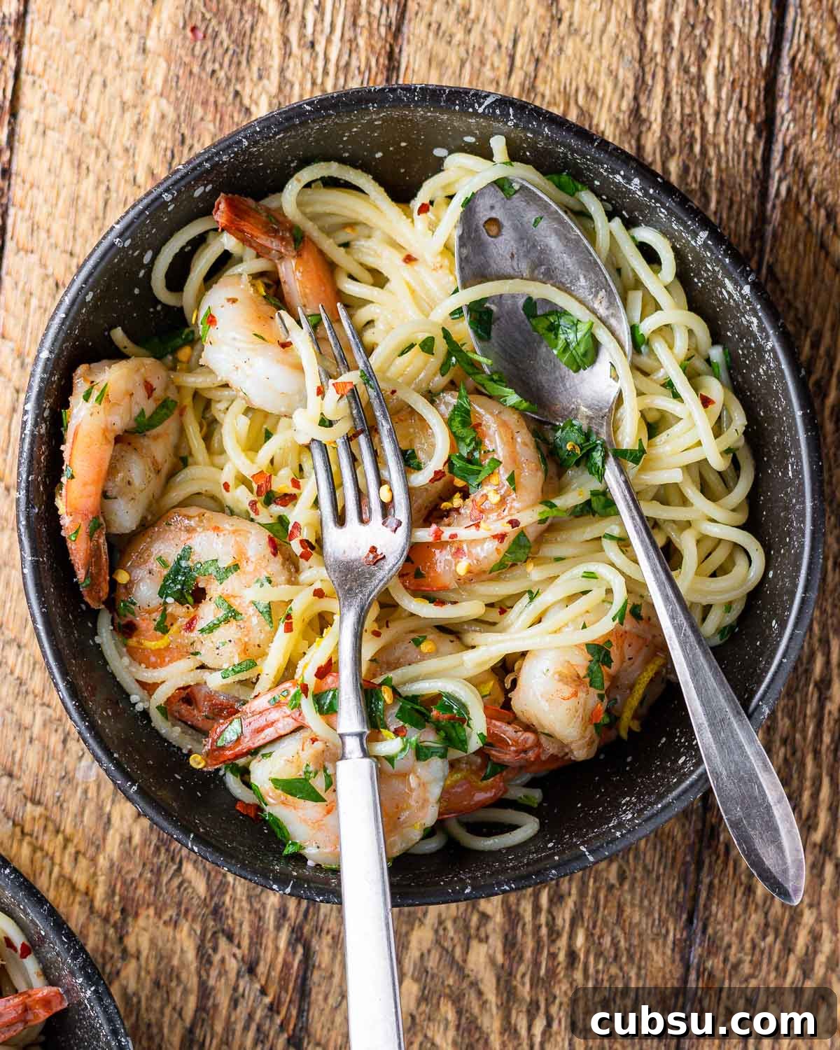 Lemon Garlic Shrimp Pasta Recipe — Zesty Weeknight Dinner 2 Lemon garlic shrimp pasta in black plate on wood table.