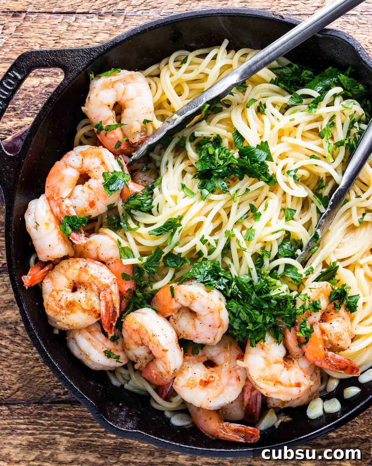 Lemon Garlic Shrimp Pasta Recipe — Zesty Weeknight Dinner 3 Lemon garlic shrimp pasta in black pan with tongs.