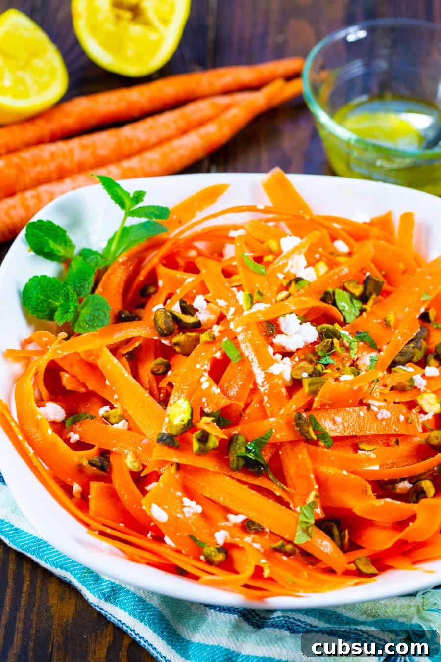 Refreshing Carrot and Feta Salad with Lemon-Dill Dressing 3 Carrot salad in a bowl with whole carrots and lemons in background.