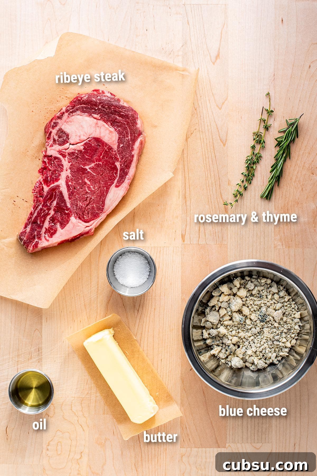 Pan-Seared Ribeye with Blue Cheese Butter Sauce 2 Raw, uncooked ingredients for cooking ribeye steak on a wooden cutting board.