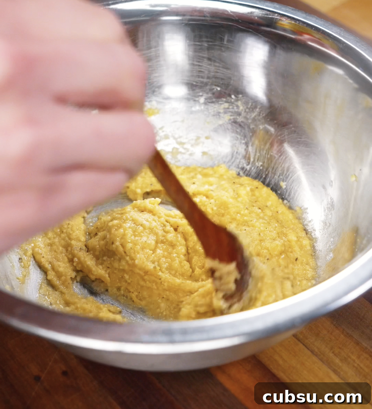 Egg yolks, miso paste, and grated parmesan are whisked together in a stainless steel bowl to form the creamy carbonara base.
