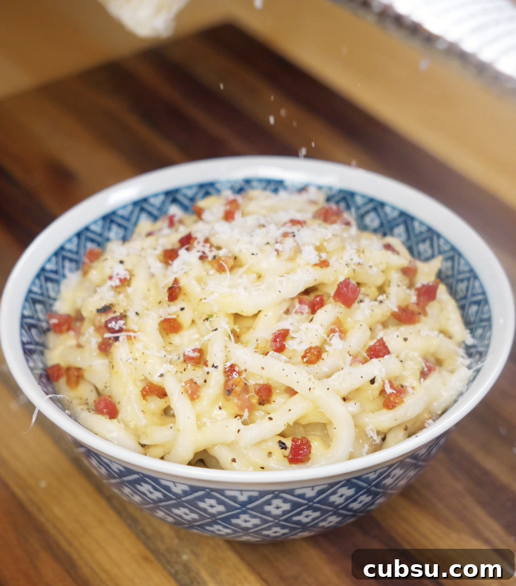 Freshly grated parmesan cheese is sprinkled over the top of the finished carbonara udon for extra creaminess.