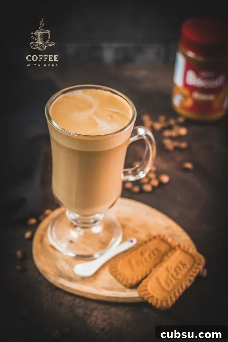 Super quick Biscoff Latte placed on small wooden plate next to two Biscoff cookies.