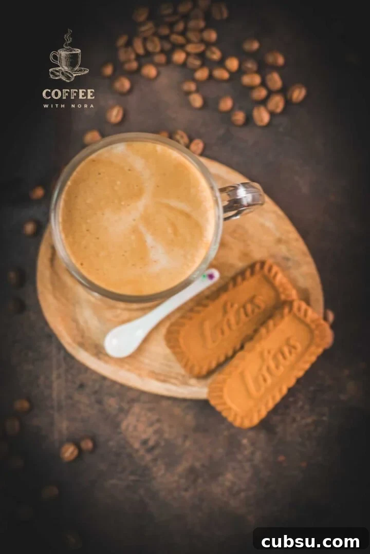 Super quick Biscoff Latte placed on small wooden plate next to two Biscoff cookies.