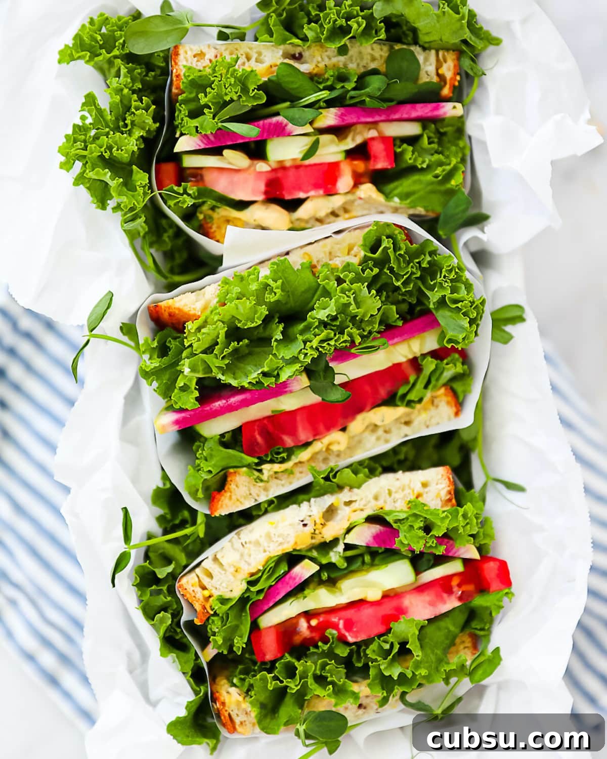 Three sandwich halves, each wrapped in white parchment paper.