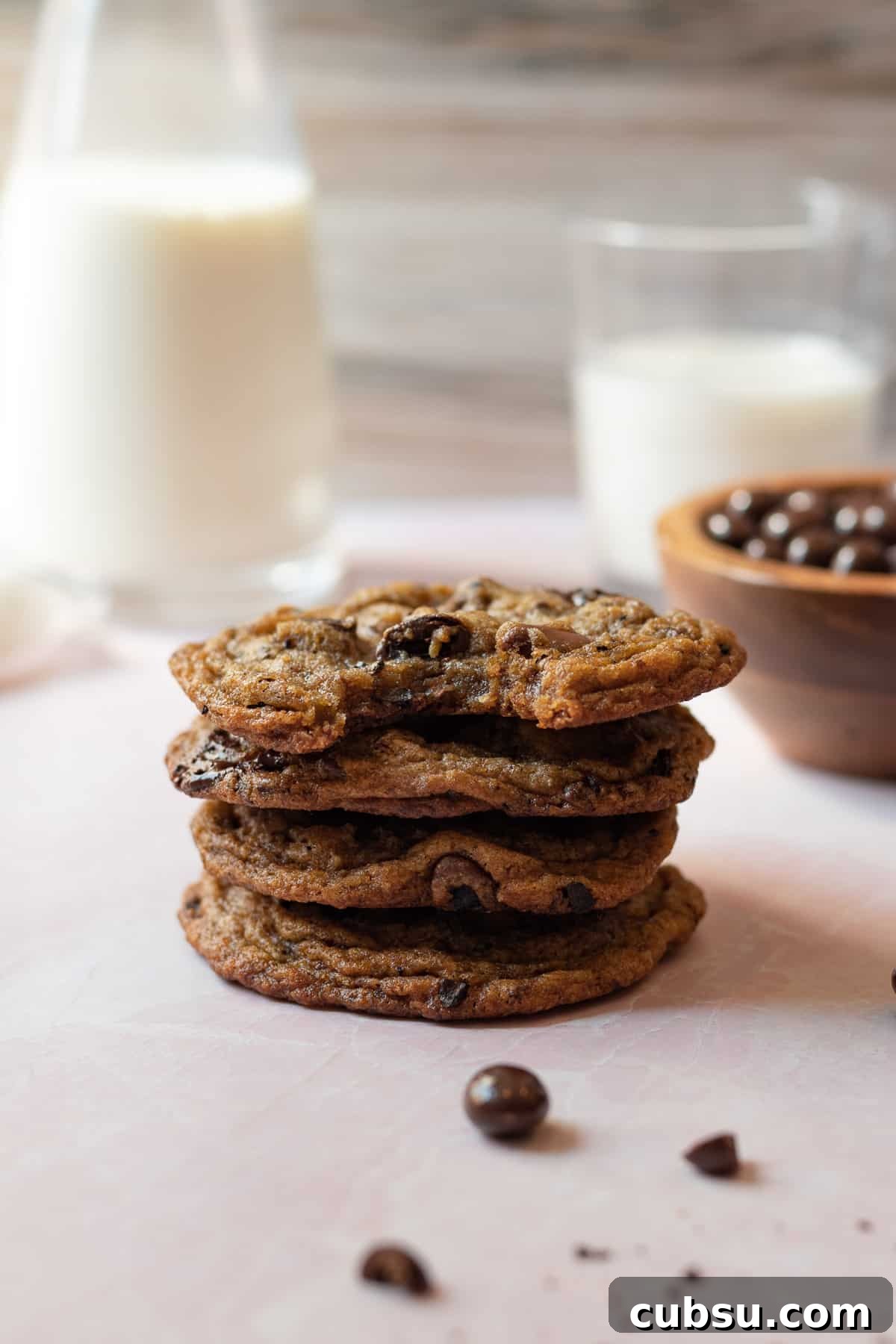 stack of espresso chocolate chip cookies with glasses of milk in the background