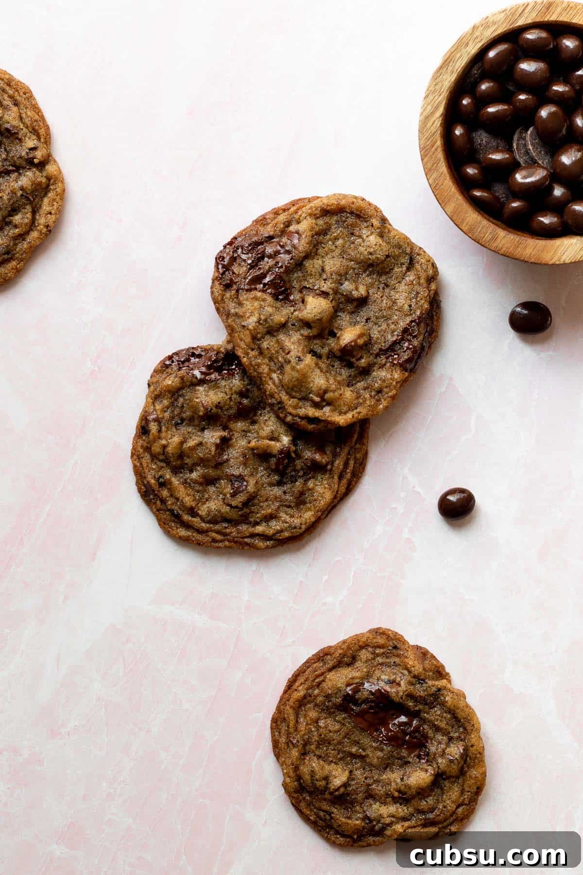 espresso chocolate chip cookies on a pink background with a small bowl of chocolate espresso beans