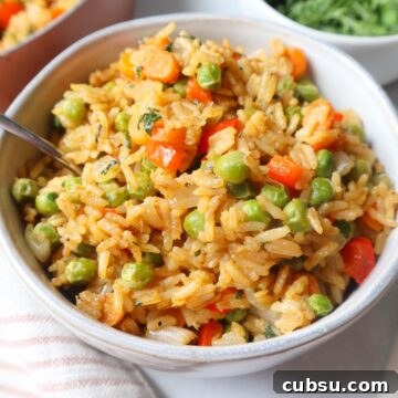 Green Curry Fried Rice Recipe: Authentic Thai Flavor in 30 Minutes 7 green curry fried rice in a white bowl with carrots, peas, and pepper, topped with fresh cilantro