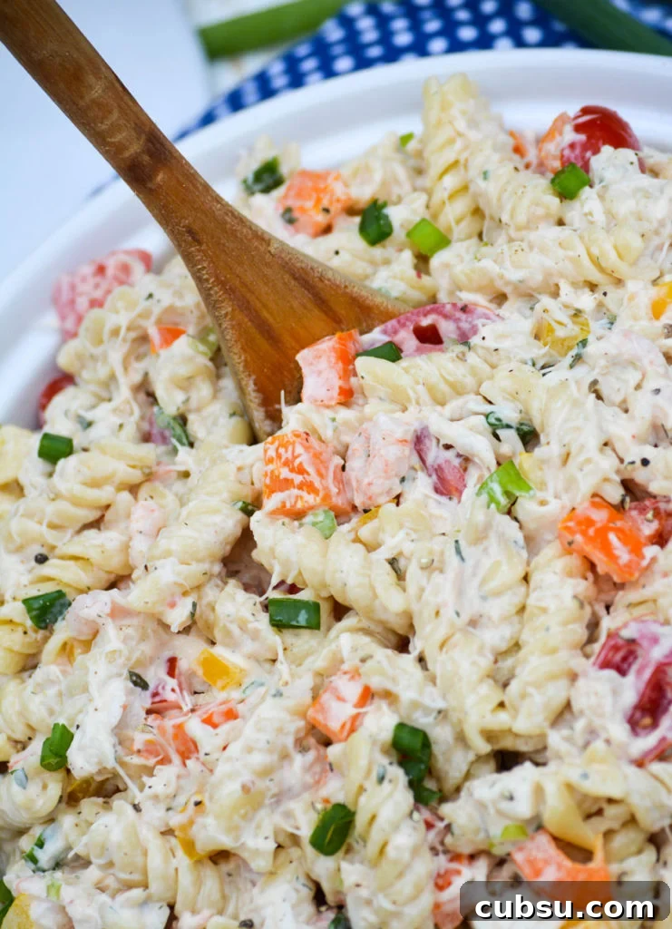 Mediterranean Seafood Pasta Salad with Lemon-Herb Dressing 4 seafood pasta salad served in a white bowl with a wooden spoon stuck in the center