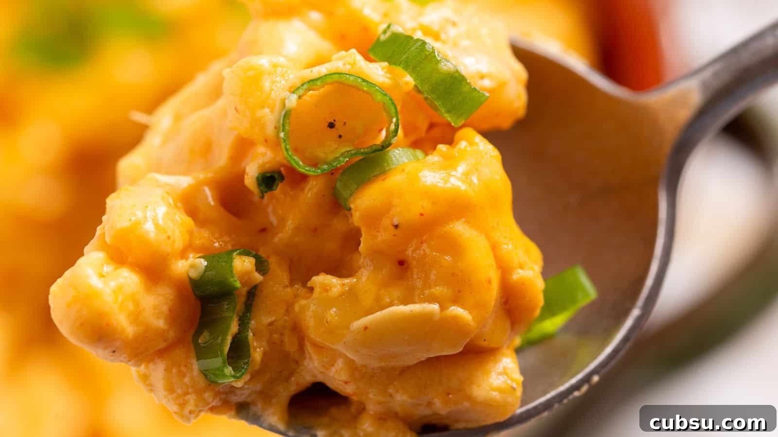 17 Timeless Grandma Recipes You Need to Try Now 11 Close-up of a spoon holding creamy mac and cheese garnished with green onions.