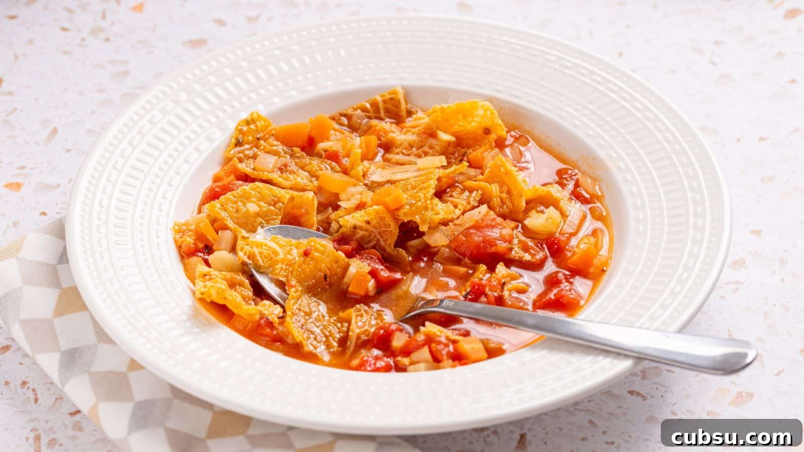 17 Timeless Grandma Recipes You Need to Try Now 13 Bowl of hearty vegetable soup with a spoon on a checked napkin.